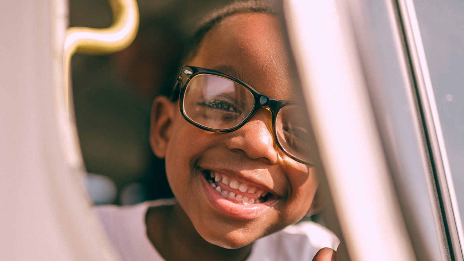 young child with glasses looking outside a car door