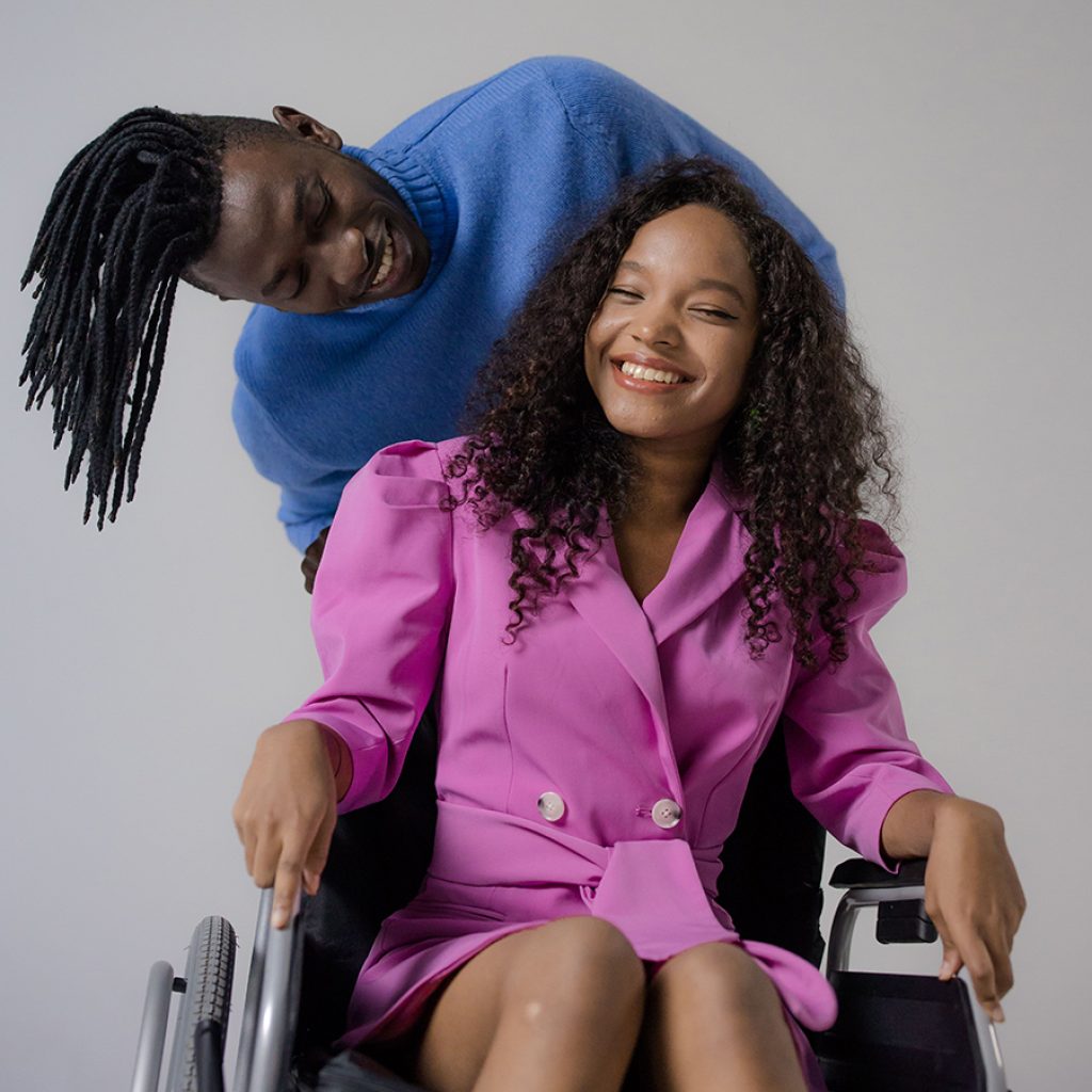 Happy couple made up of a man with dreadlocks an a lady sitting on a wheelchair