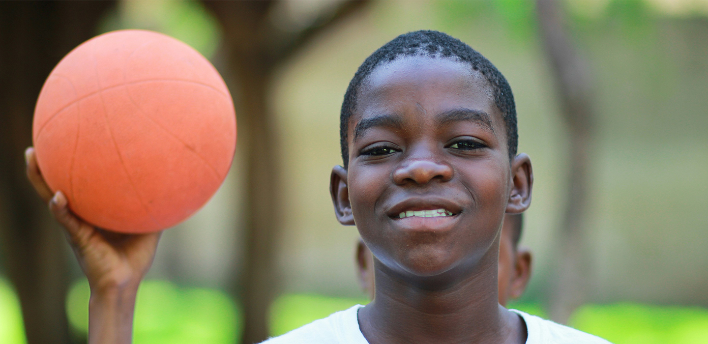 Teenage boy holding a small orange ball